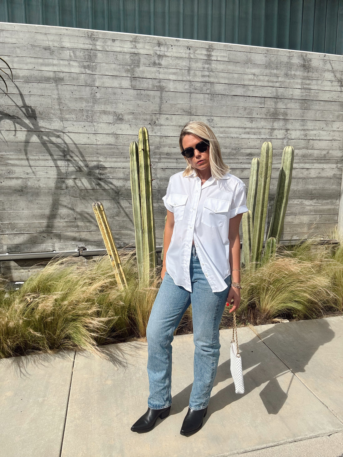 Person standing outdoors with cacti and plants in the background
