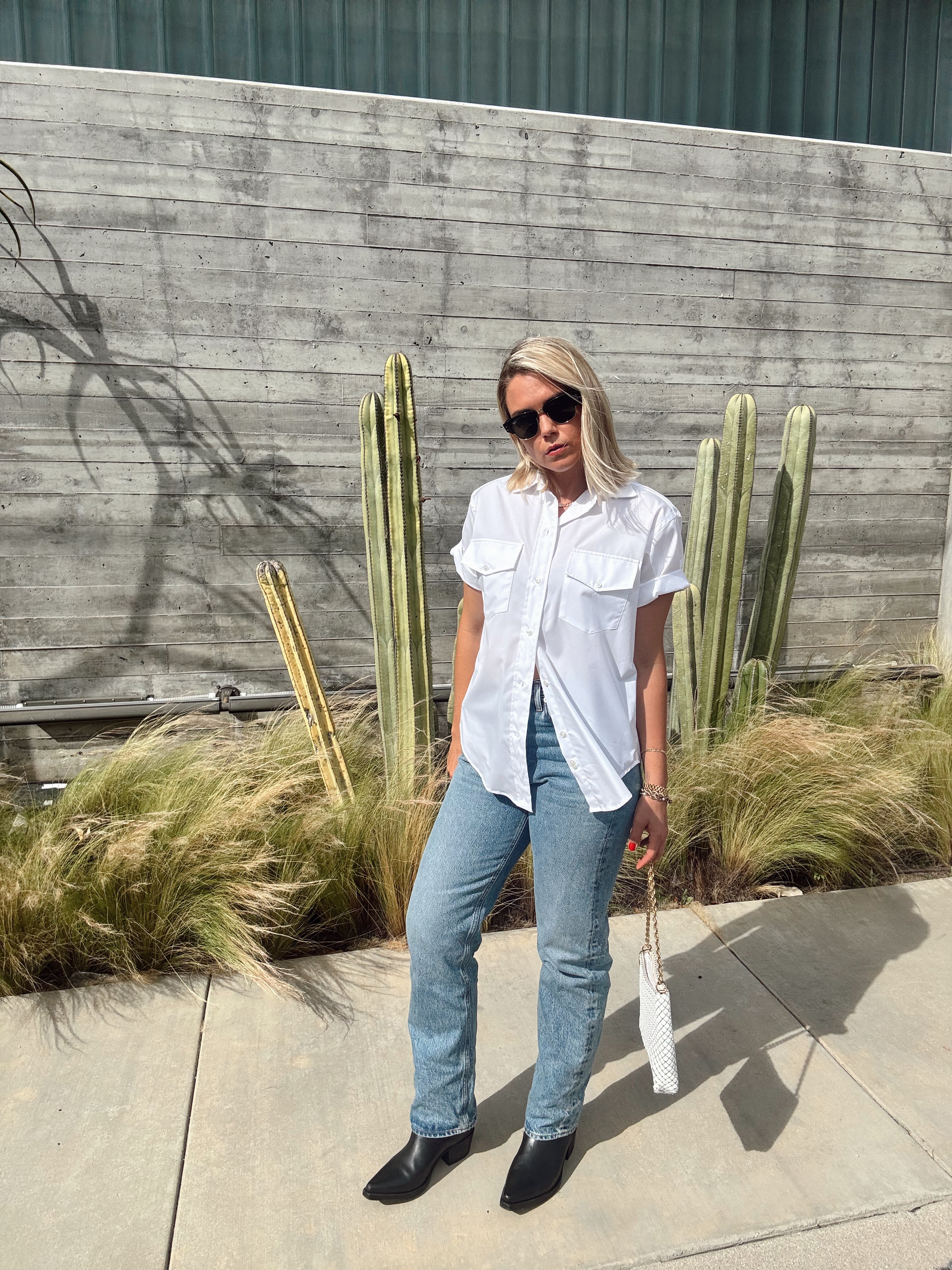Person standing outdoors with cacti and plants in the background