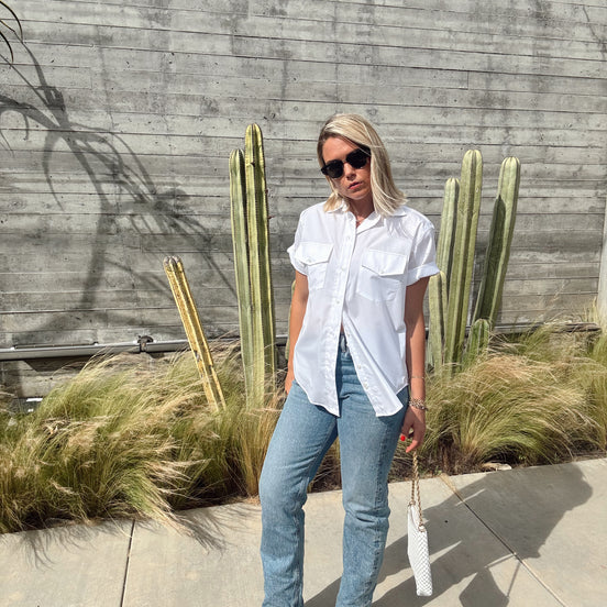 Person standing outdoors with cacti and plants in the background