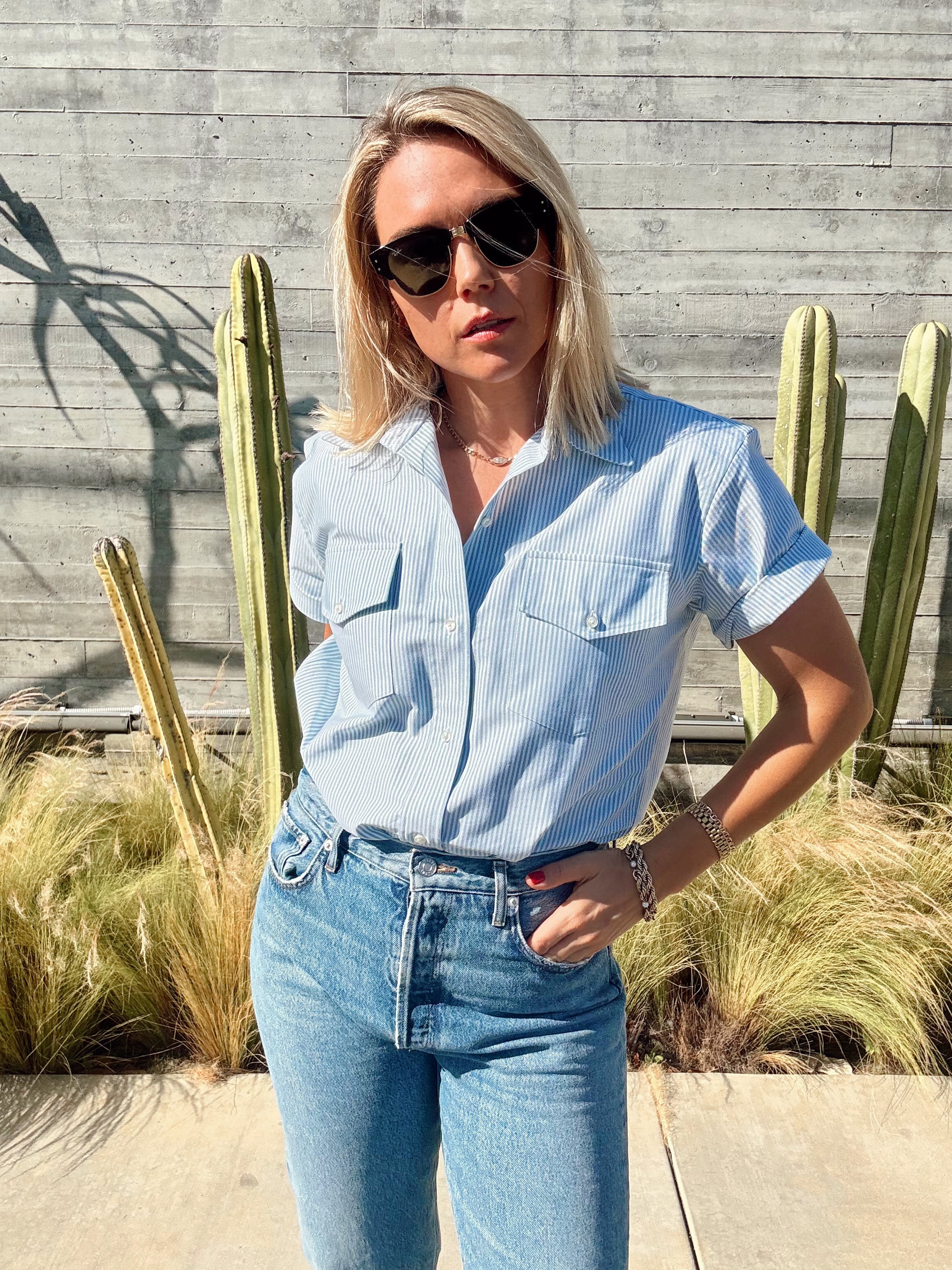 Woman in a light green shirt and jeans standing in front of cacti.