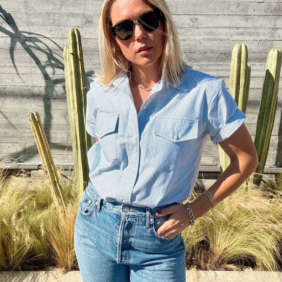 Woman in a light green shirt and jeans standing in front of cacti.